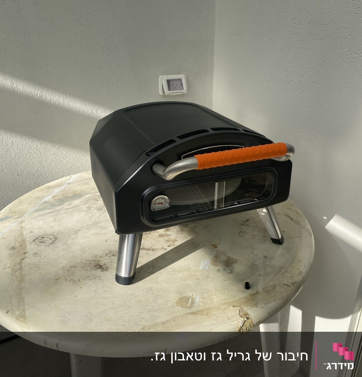 תנור אפייה קטן עם ידית כתומה על שולחן עגול